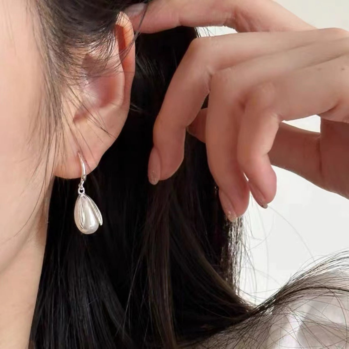 On-model close-up highlighting how the pearl drop earrings frame the face