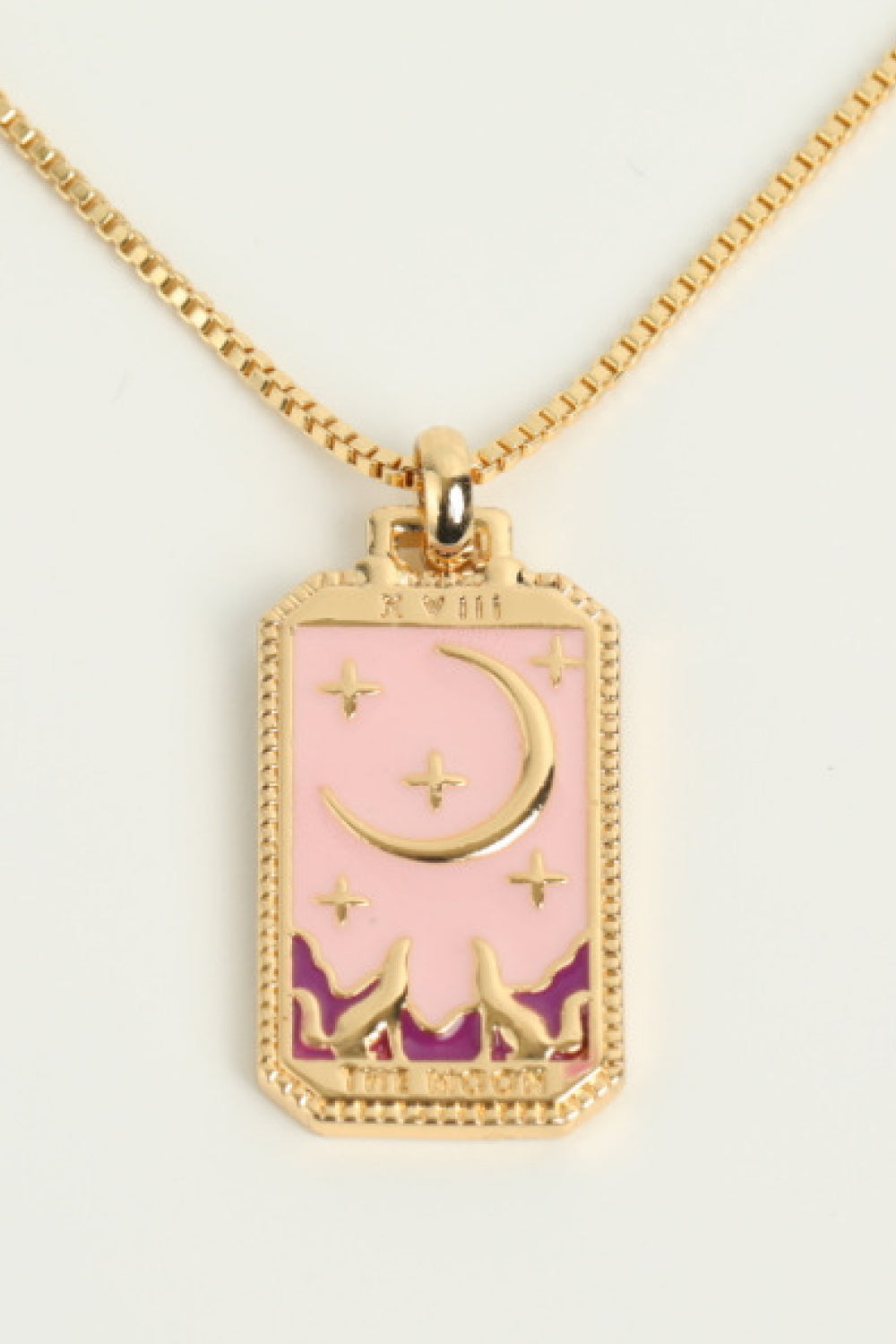 Necklace with a pink and gold pendant featuring a moon and star design on a light background.