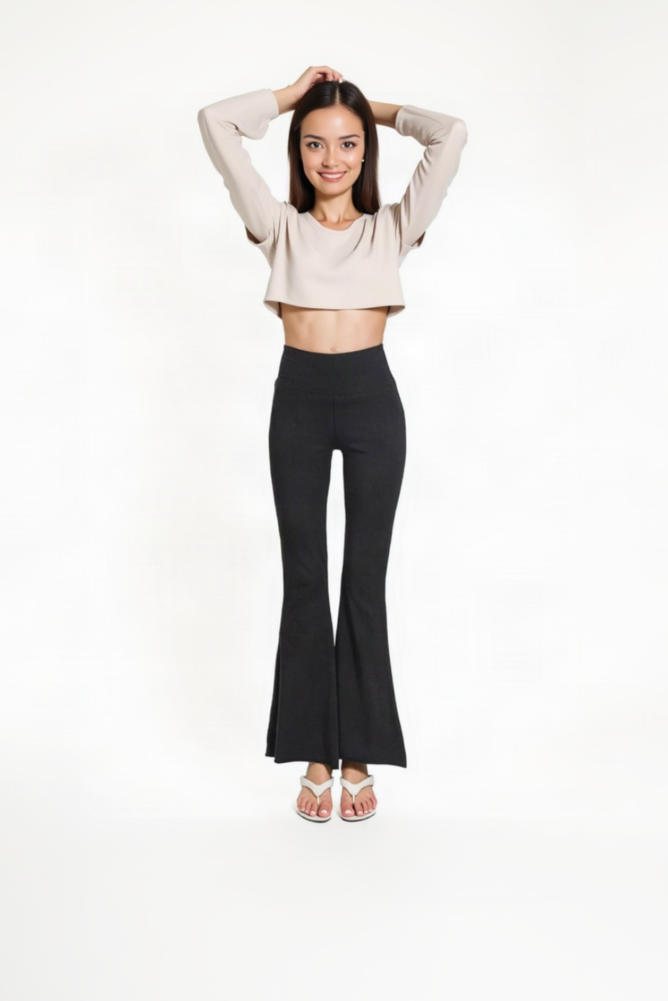 A woman modeling a two-piece outfit consisting of a beige long-sleeve cropped top and black high-waisted flared pants, standing against a solid white background.
