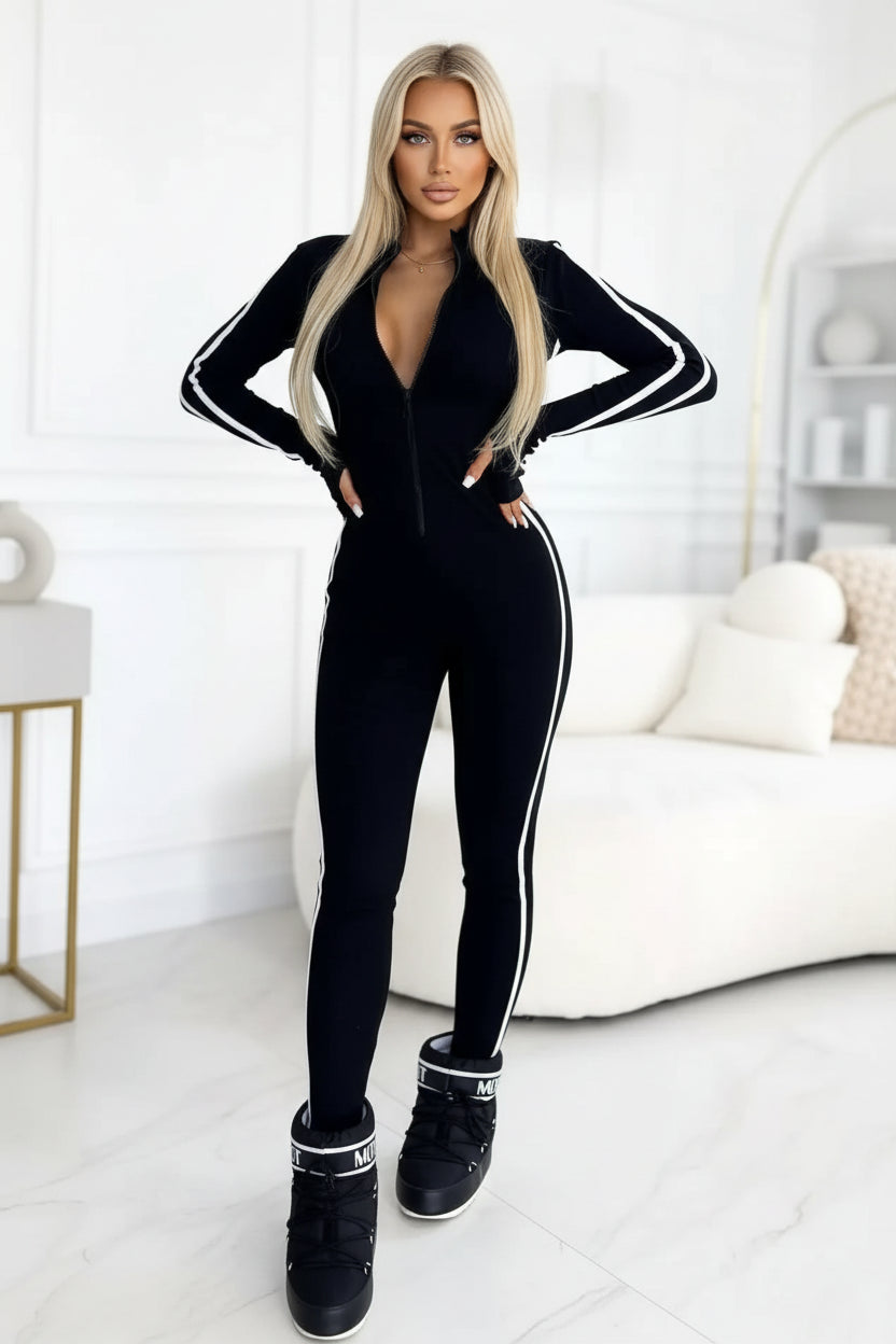 Person wearing a black tracksuit with white stripes in a minimalistic room.