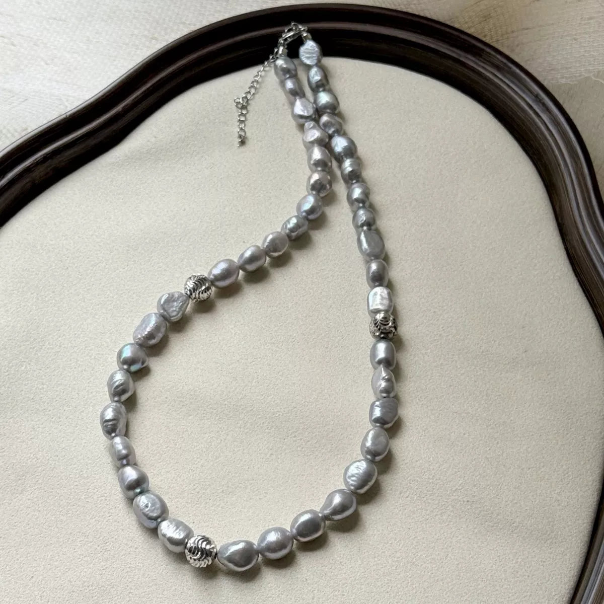 Pearl necklace on a beige cushion with a wooden frame