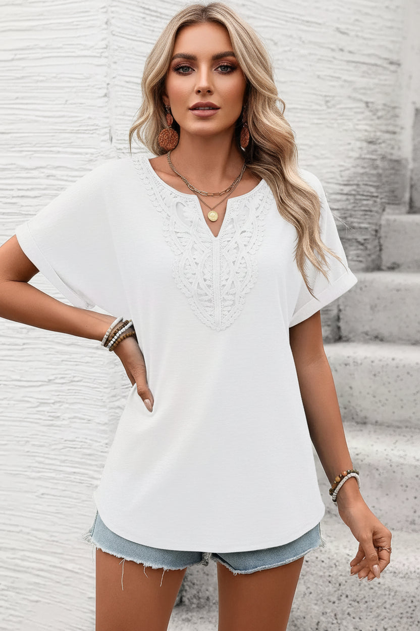 Woman wearing a white blouse and denim shorts against a textured wall.