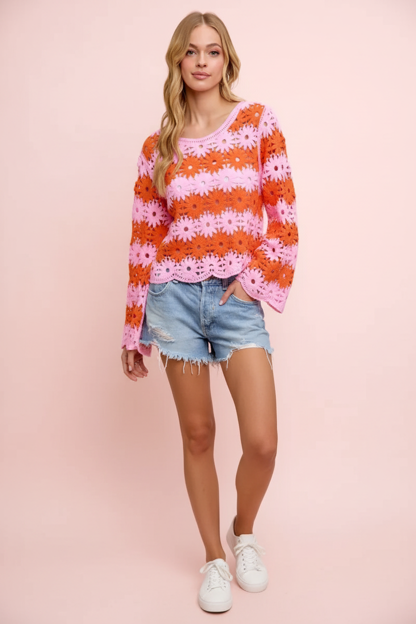 Orange and pink daisy crochet top with denim cutoffs, standing against a plain pink wall
