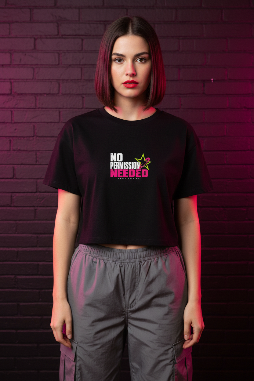 Woman with a dark bob in the black No Permission Needed boxy crop top, brick wall