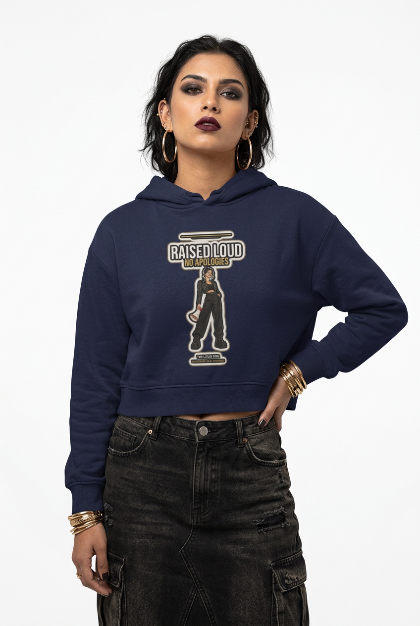 A woman modeling a navy blue cropped hoodie with a vintage-style graphic on the front that reads 'RAISED LOUD' and 'BETTER DAYS'. She is wearing dark distressed cargo pants and gold jewelry against a plain white studio background.