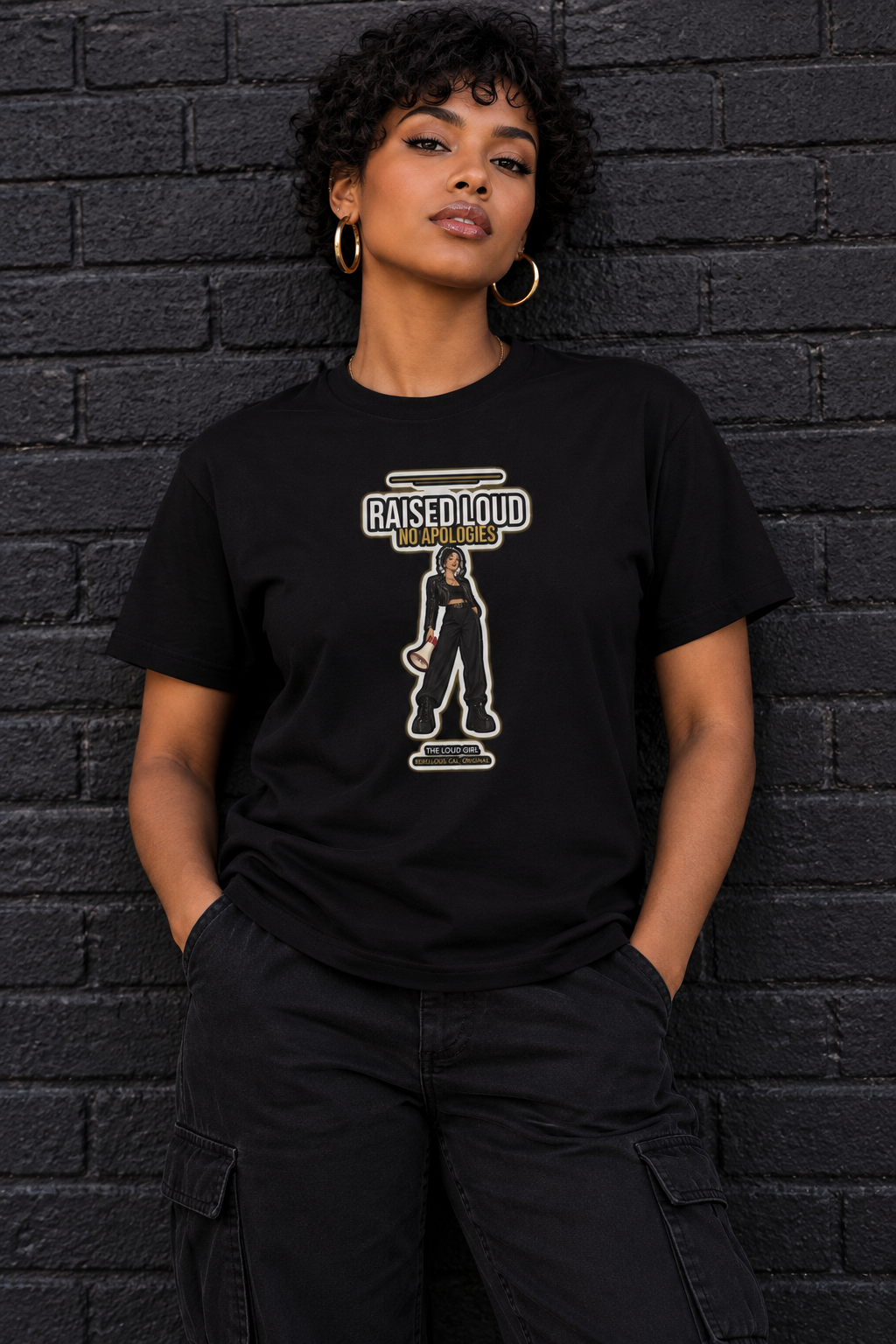 Woman with short curly hair in the black Loud Girl tee against brick
