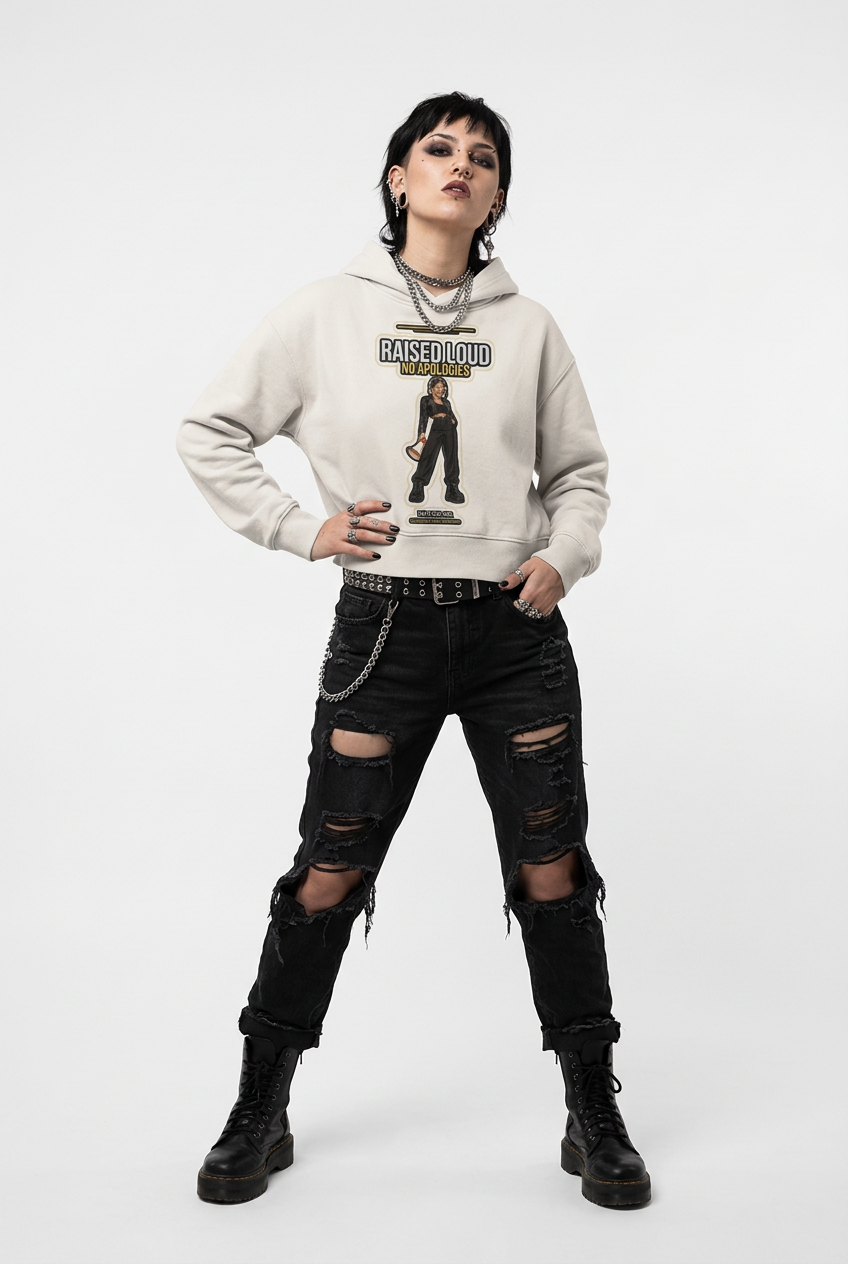 A model wearing a light beige graphic hoodie with 'RAISED FLYING' text and a central figure print, paired with black distressed jeans and black combat boots, against a plain white studio background.