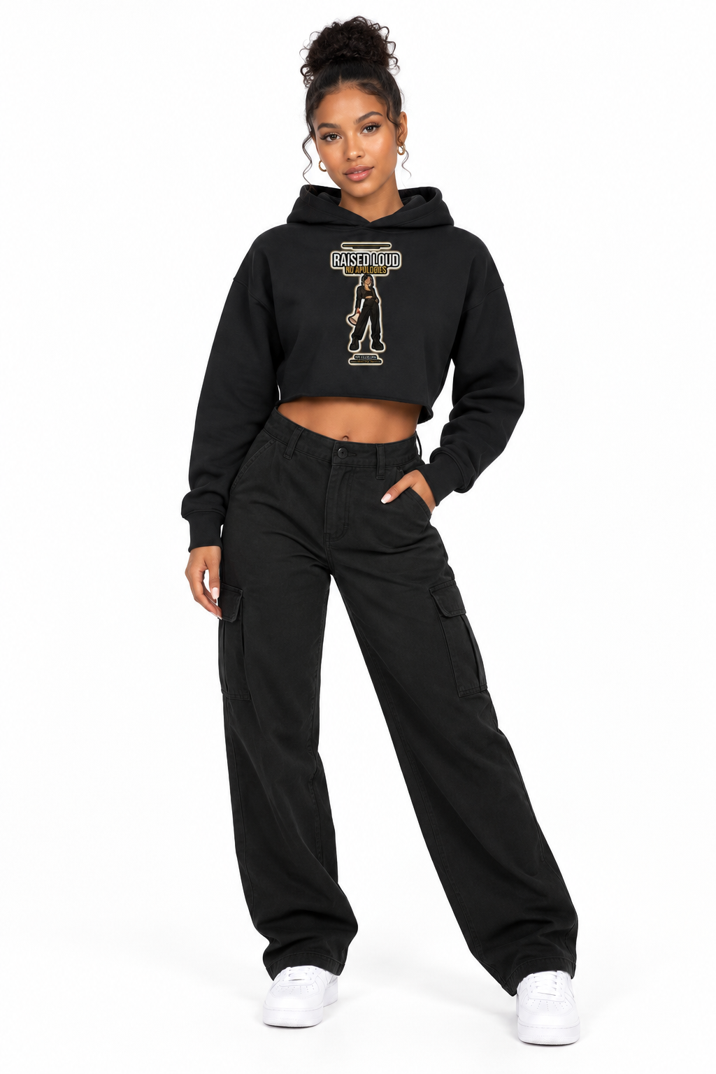A model wearing a black cropped hoodie with a gold and white graphic on the chest, paired with black cargo pants and white sneakers, against a plain white background.