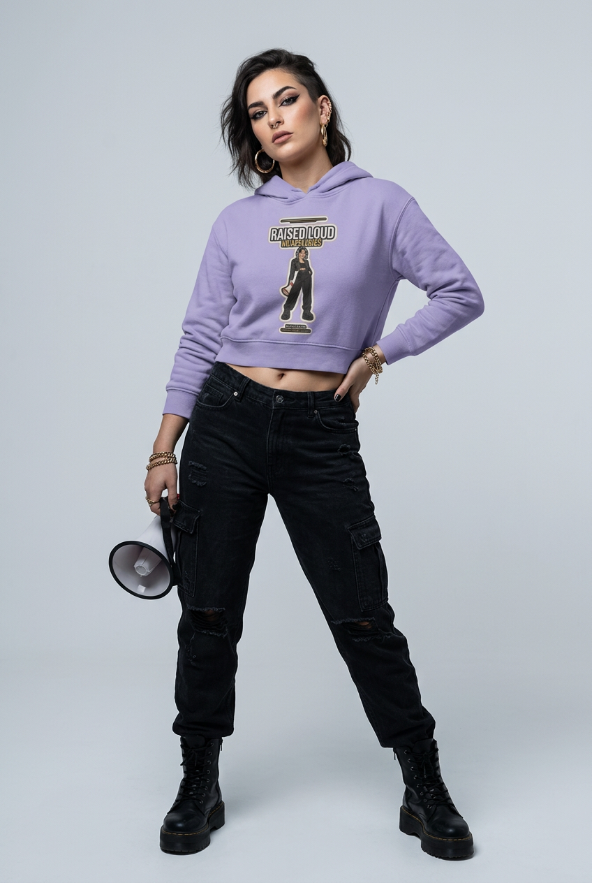 Lavender cropped hoodie over torn black denim, a megaphone resting on the studio floor