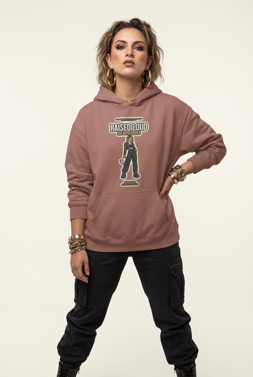 A woman modeling a dusty rose hoodie with a 'RAISED LOUD' graphic on the front, paired with black cargo pants, against a plain light beige background.