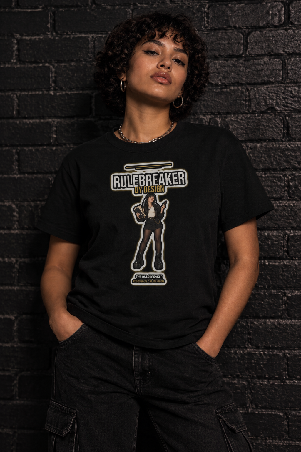 Woman with short curly hair in the black Rulebreaker tee against a dark brick wall